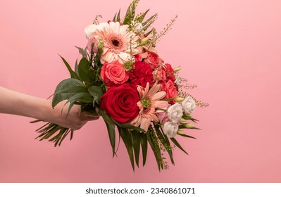 Real Human Hand Holding Beautiful Fresh Bouquet Of Flowers For Bride Or Occasion On Pink Background. Colorful Mixed Roses, Carnation Shabot, Green Leaves, Gerber. Horizontal Plane, Copy Space. - Powered by Shutterstock