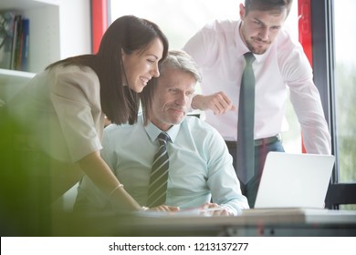 Real Life Small Business Series Attractive Business Woman With Senior Manager And Younger Businessman Having A Video Conference Call, All Three Are Looking At The Laptop That Is In Their Small Office