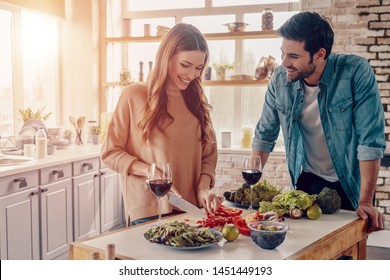 Real Love. Beautiful Young Couple Cooking Dinner And Drinking Wine While Standing In The Kitchen At Home