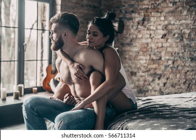 Real love. Young hipster with beard and attractive woman resting at home while sitting on bed