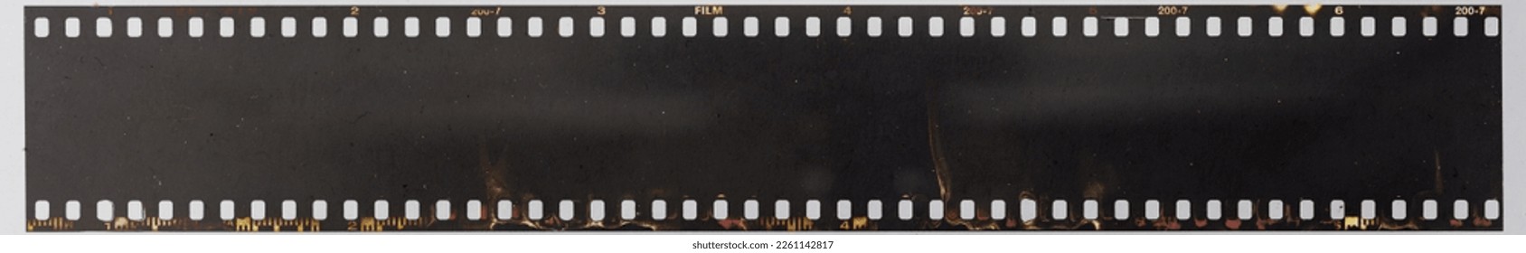 real macro photo of long 35mm filmstrip under dirty glass plate on white paper background. film material with dust. blank photo mock up. - Powered by Shutterstock