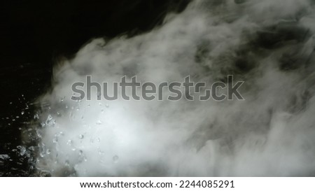 Real micro drops of hot water are sprayed in air. clouds of a thick jet are swirl. dry smoke fog. gaseous state. 
