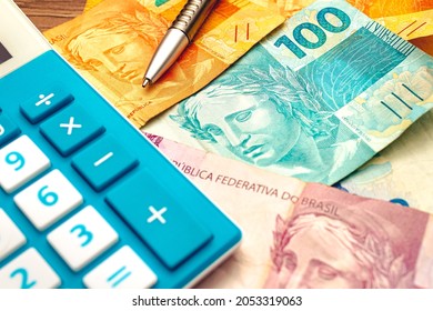 Real - money from Brazil. Brazilian Real banknotes on a wooden table with a calculator and pen in the composition. Economics and financial planning - Shutterstock ID 2053319063