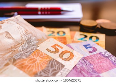 Real, Money From Brazil. Dinheiro, Brasil, Reais, Real Brasileiro. A Group Of Real Banknotes And Coins On A Table.