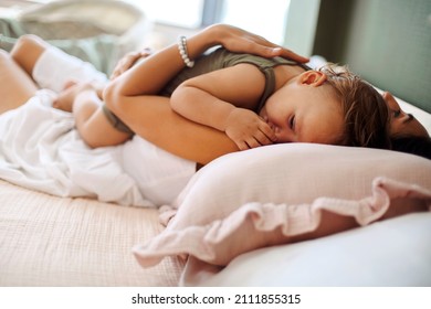 Real Motherhood. Loving Mother With Cute Baby Boy On Chest Lying In Bed At Home At Daytime, Young Mom Cuddling Her Little Son Infant While Putting Him To Sleep, Woman And Child Resting Together