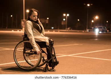 Real people, disability and handicap. Teen handicapped girl in wheelchair stay on the night parking