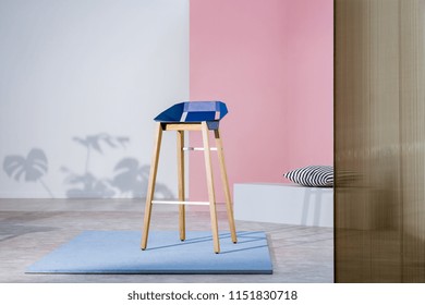 Real Photo Of An Art Gallery Interior With A Blue Bar Stool With Wooden Legs On Display Against Pastel Pink Wall