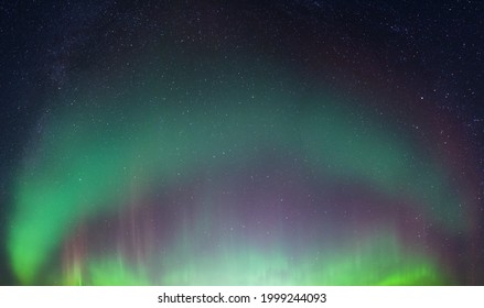 Real photo of beautiful soft Aurora Borealis - bright green curved lights on clear without clouds starry black night sky. A lot of real stars seen in Northern hemisphere, background picture