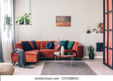 Real Photo Of Colorful Pillows On A Red Corner Couch In White Living Room Interior With Gray Rug