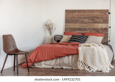 Real Photo Of A Leather Chair In A Natural Bedroom Interior With A Wooden Bed, White Walls And String Of Lights