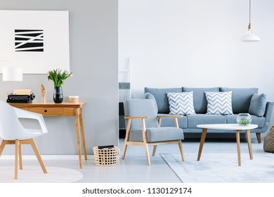 Real Photo Of A Living Room Interior With Study Space. Typewriter On A Wooden Desk Next To A Sofa With Two White Cushions And Houndstooth Pattern Armchair