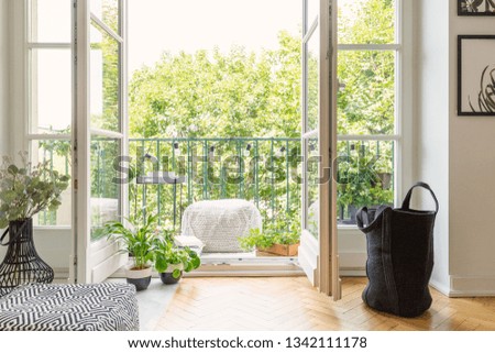Real photo of open door to balcony with many fresh plants, lights, material pouf and view on urban jungle [[stock_photo]] © 