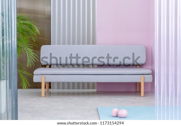 Real photo of a pastel living room interior with a\
palm next to a gray couch