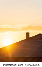 Real Photo Of Photovoltaic Panels On The Roof Of The House Against The Setting Sun. Background With Copy Space In Warm, Sunny Tones, Perfect For Solar Energy Materials