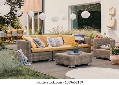 Real photo of a rattan garden furniture set with lamps and table in the background