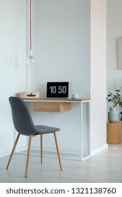 Real Photo Of A Simple Home Office Interior With A Laptop On A Wooden Desk And A Gray Chair