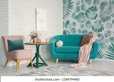 Real Photo Of Turquoise Couch And Pastel Pink Armchair Standing In Bright Living Room Interior With Flamingo Poster On Brick Wall And Leafy Wallpaper