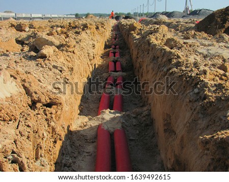 Real process of construction on a building site, laying orange pipes, debris, autumn, trench, view of underground utilities, dug pipes, pouring foundation, Rusted gas and oil pipeline
