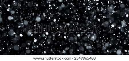 Real snowfall over black background. Abstract snowy white particles falling for winter weather overlay or cold snowfall background. Heavy snow storm.