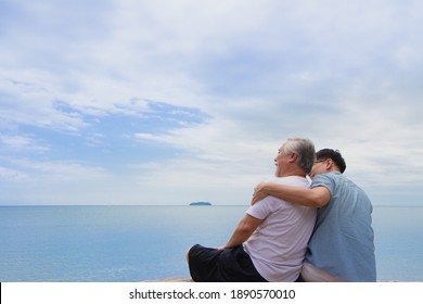 Real view of Senior retirement age and son sitting with ocean background. asia father and son feeling happiness looking blue sky and sea relax time