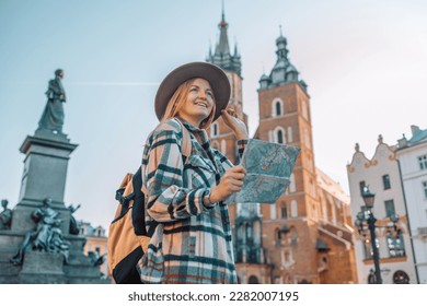 Real view of traveller woman walking on old Market Square in Krakow holding tourist map. Travel and active lifestyle concept. High quality photo - Powered by Shutterstock