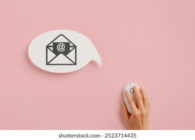 real white speech bubble with opened email sign and hand using wireless mouse on pink background for communication, online service concept