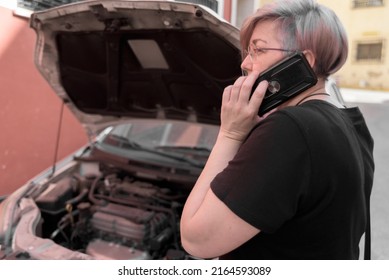 Real Woman With The Hood Of The Car Open On The Street In A Village Telephones The Insurance Company To Ask For Help From A Tow Truck.