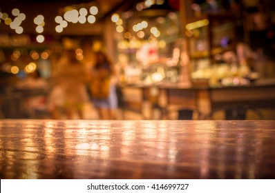 Real wood table with light reflection on scene at restaurant, pub or bar at night. Blurred background for product display or montage your products with several concept idea and any occasion.