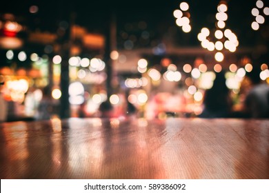 Real Wood Table With Light Reflection On Scene At Restaurant, Pub Or Bar At Night. Blurred Background For Product Display Or Montage Your Products With Several Concept Idea And Any Occasion.