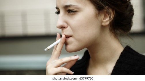 Real Young Woman Smokes On The Street, Selective Focus