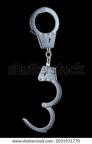 real zinc plated steel police handcuffs half-opened hanging vertically, isolated on black background.