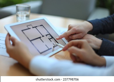 Real-estate agent showing house plans on electronic tablet