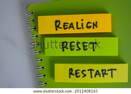 Realign, Reset, Restart write on sticky notes isolated on Wooden Table.