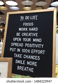 Realistic To Do List white text on black letter board in a shop. Focus. Work Hard. Be Creative. Open Your Mind. Spread Positivity. Take Chances. Smile More. Breathe. Positive Quotes. - Image