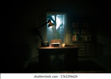 A Realistic Dollhouse Living Room With Furniture And Window At Night. Man Sitting On Table In Dark Room. Concept Of Stay Home During Global Virus Pandemic. Selective Focus.