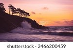 Realistic photographic of a purple sunset over a cliff with trees. Very rough waves are crashing through the rocks.