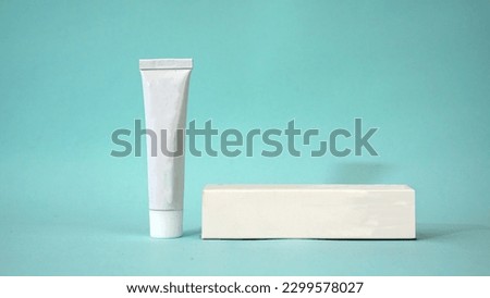 Realistic white tube mockup with a cardboard box for toothpaste, cream, cosmetic and gel. White tube with clean blue background                                     