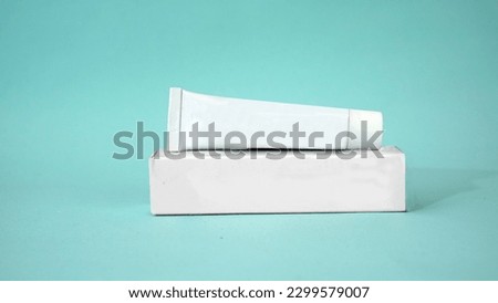 Realistic white tube mockup with a cardboard box for toothpaste, cream and gel. White tube with clean blue background                                     