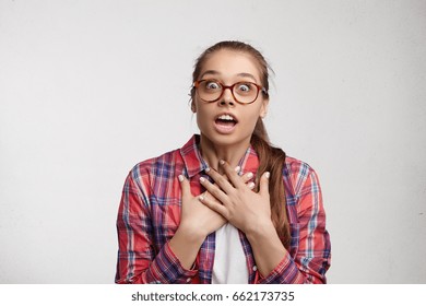 Is It Really So? Excited Woman In Eyeglasses And Red Checked Shirt Looking With Bugged Eyes, Opened Mouth And Bated Breath Not Believing In What She Heard Unexpected To See Someone. Puzzled Situation