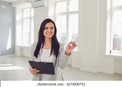 Realtor agent is a realtor with keys in hand against the background of a white real estate room apartment home. - Shutterstock ID 1673000752