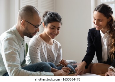 Realtor businesswoman during meeting with multi-ethnic couple showing where put signature affirming rental contract, fill bank application form process, closing deal, mortgage, lease agreement concept