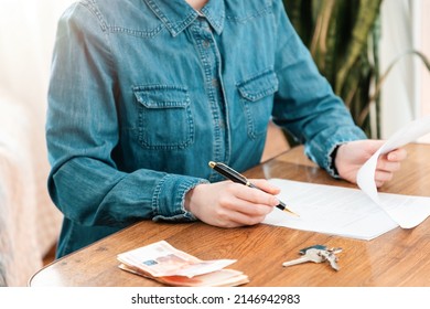 Realtor Fills Out A Contract For The Lease Or Purchase Of Real Estate. Close-up Of Hands And A Table With Money, Documents And Keys. Mortgage And Lending Concept.