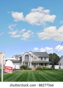 Realtor Red For Sale Sign On Lush Green Landscaped Front Yard Lawn Of Large Beautiful Suburban Home In Residential District