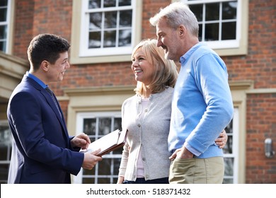 Realtor Showing Mature Couple Around House For Sale