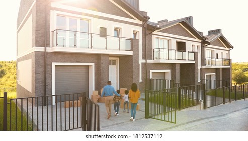 Rear of African American family with small children walking and moving in new home at suburb. Mother and father carrying boxes at house and little kids helping. 