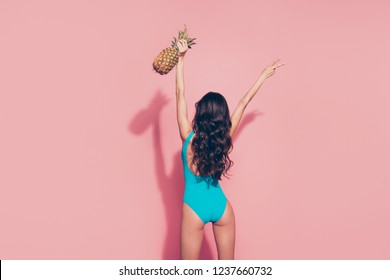 Rear back behind view portrait of slim fit thin gorgeous graceful charming adorable nice attractive wavy-haired lady holding raising ananas up v-sign isolated over pink pastel background