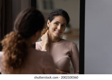 Rear back smiling 30s hispanic caucasian woman looking at mirror, checking appearance before leaving apartment, getting ready for job or walk, satisfied with neat fit look, admiring herself at home. - Powered by Shutterstock