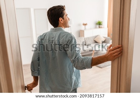 Rear back view of excited young man walking in his apartment, entering new home, happy young guy standing in doorway of modern flat, looking at design interior, coming inside, selective focus Foto d'archivio © 