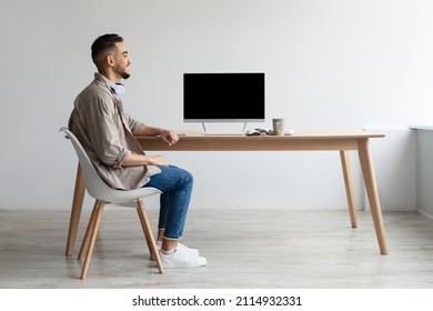 Rear back view of happy Middle Eastern man looking at blank empty computer monitor sitting at table at workplace, watching webinar or having online web video call, free copy space. mockup template - Shutterstock ID 2114932331