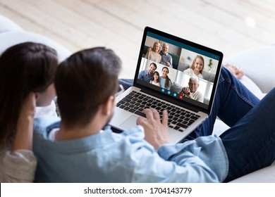 Rear back view married couple resting and chatting with relatives via videoconference videocall application, laptop screen view over spouse shoulder. Distant virtual communication, modern tech concept - Shutterstock ID 1704143779